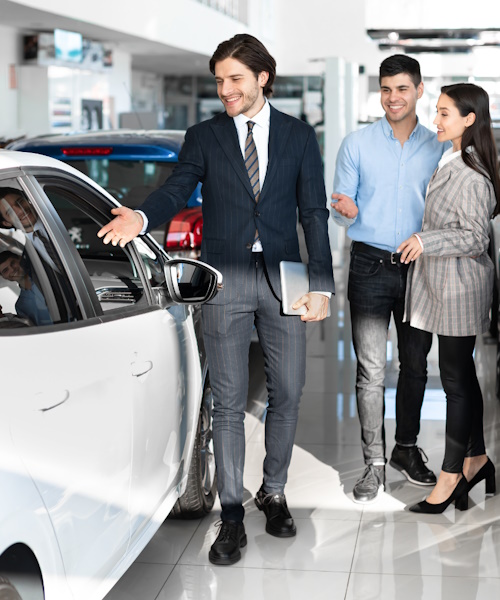 A photo of a car dealer selling a car to a couple